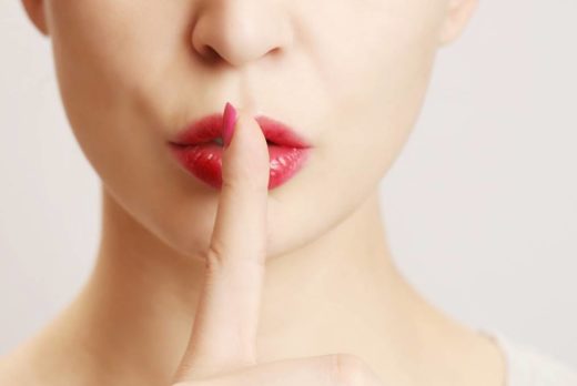 Infidelity, adultery and secrets. Woman holding finger in front of mouth to indicate secret.