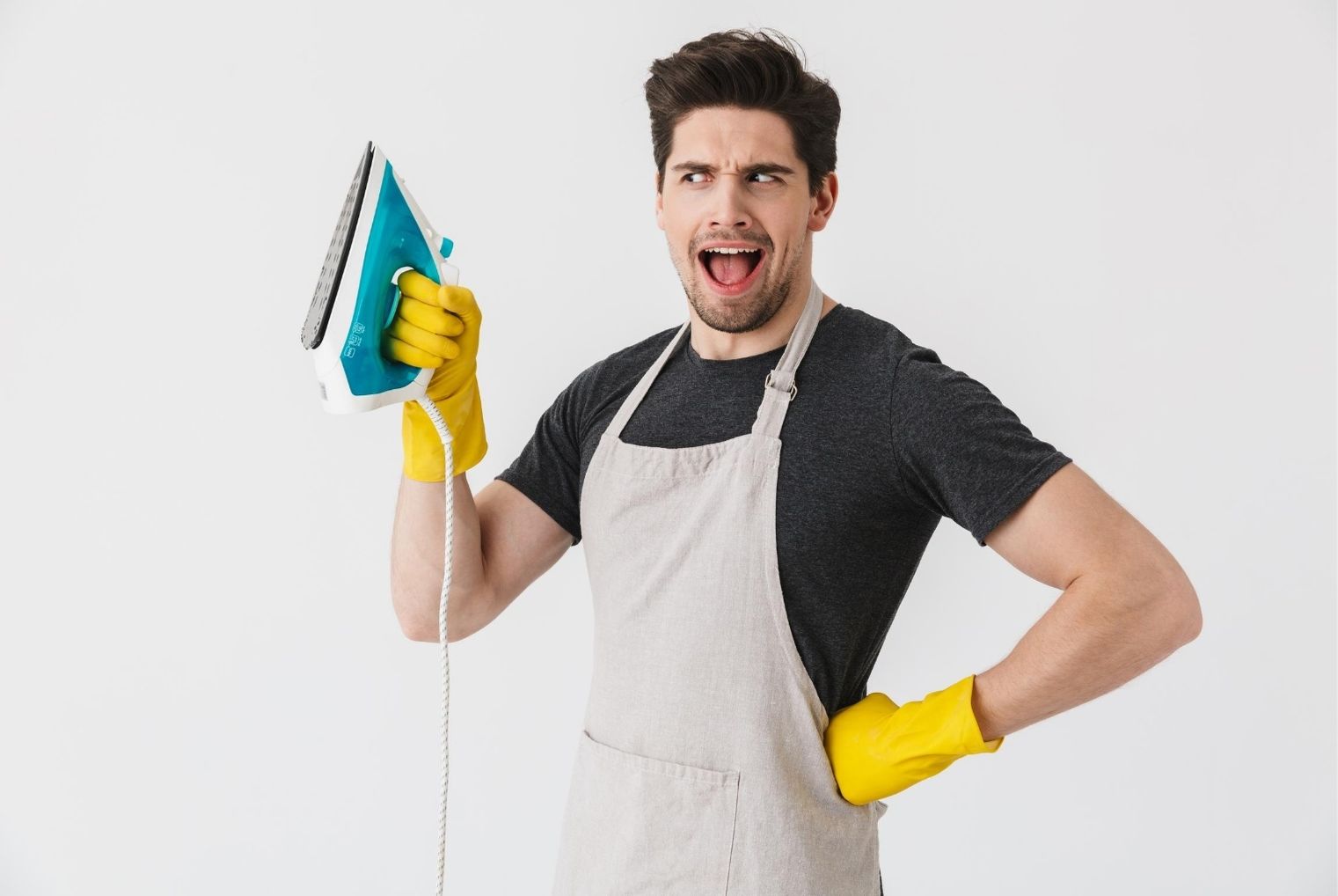 Man holding iron and wearing apron and cleaning gloves