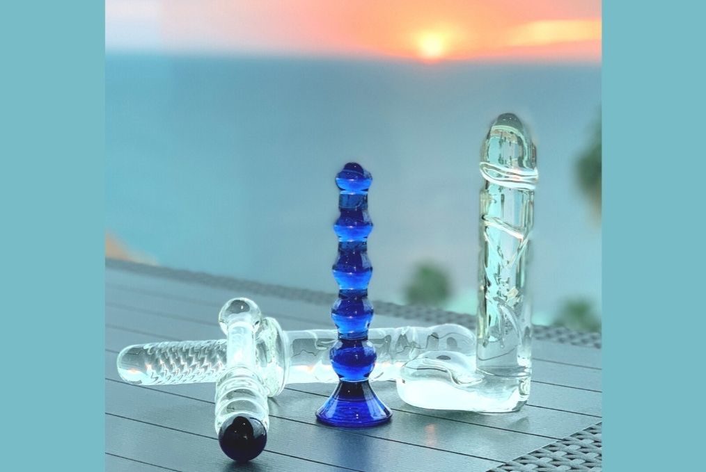 four glass dildos on table in sunset. Toy Tuesday blog image Elisabet Barnes